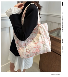 Detail of floral tote bag with green botanical prints worn by model in a suit