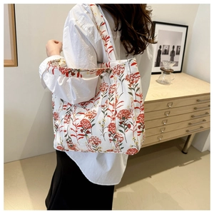 Detail of canvas tote bag featuring red floral print and wide comfortable shoulder straps