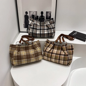 Three oversized plaid tote bags with leather straps displayed on a minimalist white stage