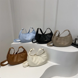 Minimalist leather hobo bags in five colors displayed on an artistic pedestal