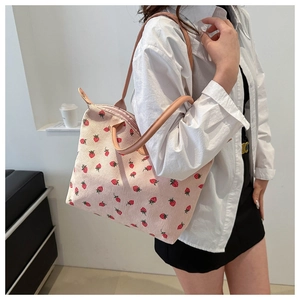 Detailed texture of pink corduroy tote bag with red strawberry print and leather strap