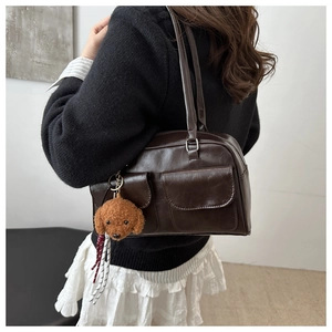 Détail d'un sac oreiller en cuir marron brillant avec poches et porte-clés chien en peluche
