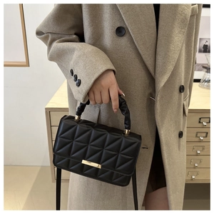 Detail of quilted black handbag featuring gold buckle and pleated handle texture