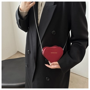 Close-up of red heart-shaped mini crossbody bag with gold lettering and silver chain strap
