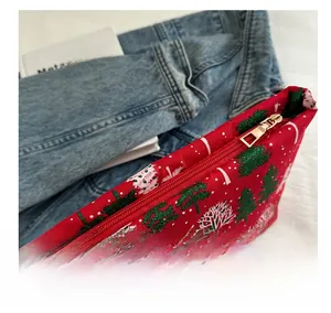Détail de la pochette de Noël rouge avec motifs d'arbres à paillettes et zip doré