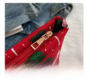 Gros plan de la fermeture éclair dorée sur une pochette de Noël rouge à motifs de sapin