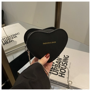 Close-up of heart-shaped mini crossbody bag with gold text and silver chain strap