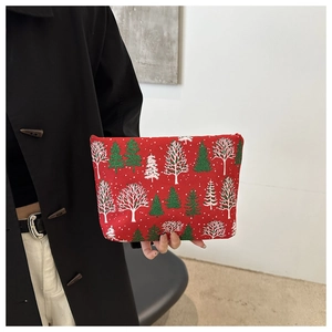 Rote Canvas-Kosmetiktasche mit Weihnachtsbaum-Muster, von einem Model handgehalten