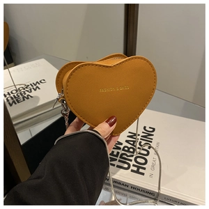 Detailed close-up of heart-shaped mini bag with metal chain and zipper in mustard yellow