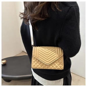 Detail van beige gewatteerde crossbodytas met brede stoffen riem gedragen door een vrouw