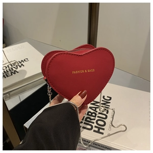 Close-up of a red heart-shaped mini chain bag with fashion gold text and silver strap