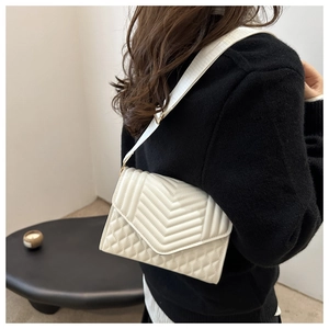 Detail van witte gewatteerde crossbodytas met chevronpatroon en brede schouderriem