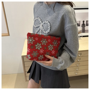 Nahaufnahme der roten Weihnachtskosmetiktasche mit Schneeflocken von einem Model gehalten