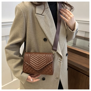 Detailopname bruine gewatteerde crossbodytas met brede riem op beige blazer-outfit