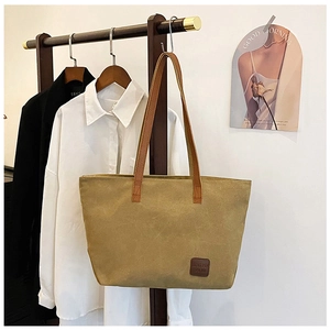 Détail d'un grand sac cabas en toile gingembre avec des poignées en cuir marron foncé