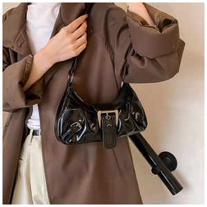 Detail of black pleated shoulder bag with oversized silver buckle and rivets