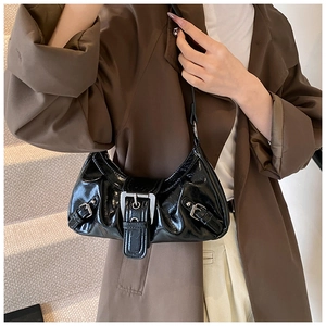 Detail of black glossy baguette bag with silver buckle and stylish pleated design