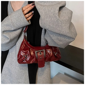 Detail of burgundy ruched underarm bag with glossy patent leather and metallic buckle