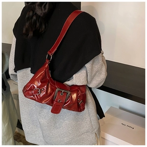 Detail of dark red glossy shoulder bag with artistic pleats and silver buckle hardware