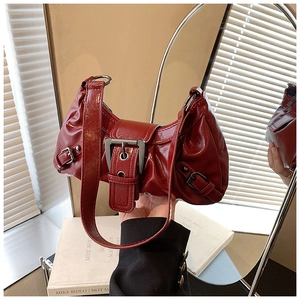 Close-up of red glossy vintage baguette bag with oversized buckle and textured finish