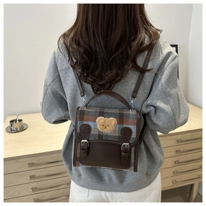 Close-up of a stylish plaid backpack with a cute teddy bear patch on a female model