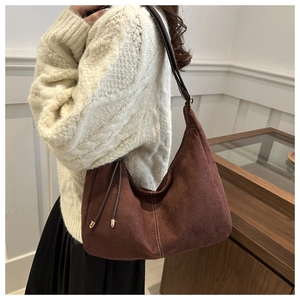 Détail du sac hobo en daim marron foncé avec surpiqûres contrastées et cordon doré