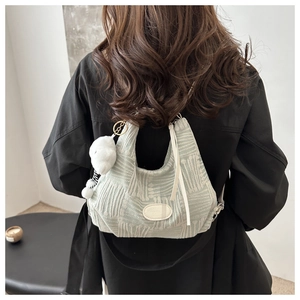Detail of light green quilted tote bag with soft texture and white plush charm accessory