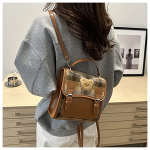 Detail of checkered plaid backpack featuring a cute teddy bear patch and PU leather trim
