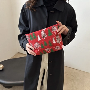Rote Weihnachts-Kosmetiktasche mit Baummotiv, getragen von einem Modell im schlichten Stil