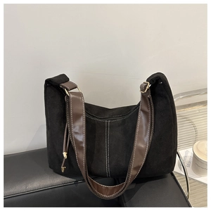 Détail du sac en daim noir avec coutures blanches contrastées et bandoulière marron