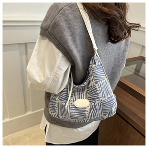 Close-up of blue and white plaid tote bag with white leather patch on a model