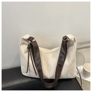 Détail du sac à bandoulière beige texturé avec sangle marron et pompon décoratif