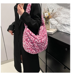 Detailed close-up of a large pink leopard print plush hobo bag worn with a black blazer