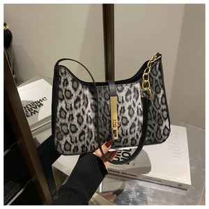Détail du sac léopard avec chaîne dorée et bordure noire porté par un mannequin