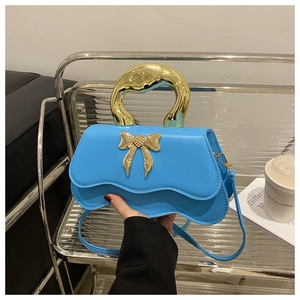 Detail of blue wavy small square bag featuring a bold gold handle and metal bow buckle