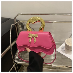 Detail of pink crossbody bag with golden bow clasp and unique wavy bottom edge design