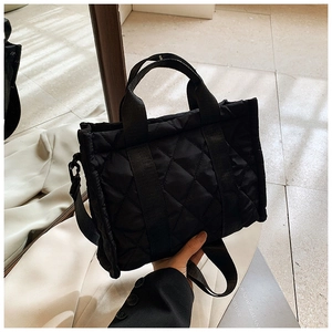 Detail of black quilted tote bag showing diamond stitching and adjustable shoulder strap