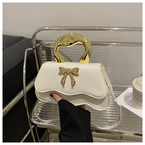 Detail of cream crossbody bag with lava metal handle and bow heart decoration