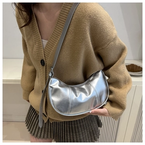 Vue latérale d'un sac demi-lune argenté porté par un mannequin dans un style épuré