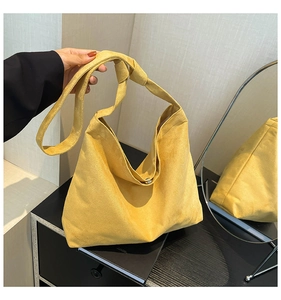Detailed macro view of yellow frosted suede tote bag showing knot strap and magnetic closure