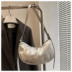 Detailed view of silver metallic crescent bag featuring vertical quilted texture and strap
