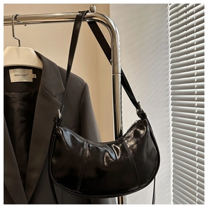 Detailed view of black crescent underarm bag with glossy finish and sleek stitching