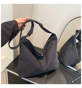 Detail of black matte suede tote bag with knotted shoulder strap and magnetic closure