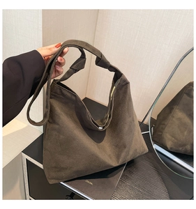 Detail of dark brown suede tote bag featuring a stylish large knot design on the shoulder strap