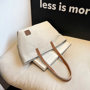 Grand sac fourre-tout en toile crème avec anses en cuir marron et logo sur canapé