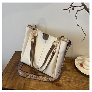 Detail of a minimalist tote bag featuring cream faux leather and jacquard woven strap