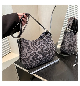 Detail of gray leopard print hobo bag with faux fur texture and gold buckle on a desk