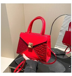 Close-up of red crocodile pattern leather handbag with gold rivet and mirror reflection