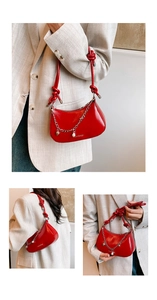 Detail of red glossy leather shoulder bag featuring silver chain, pearls and heart pendant