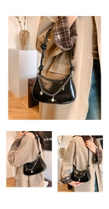 Detail of black crescent shoulder bag featuring silver chain and pearl heart charms